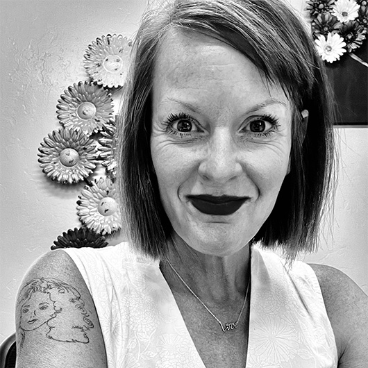 Black and white photo of a woman in a white shirt, and a flower sculpture behind