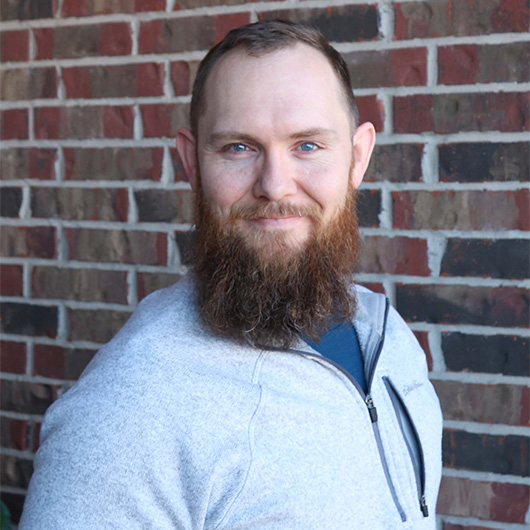 Smiling man with a beard wearing a half zip fleece