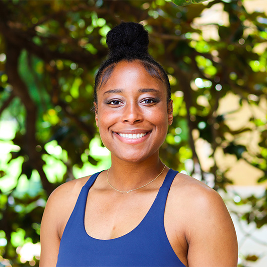 Woman in a blue tank top in front of trees