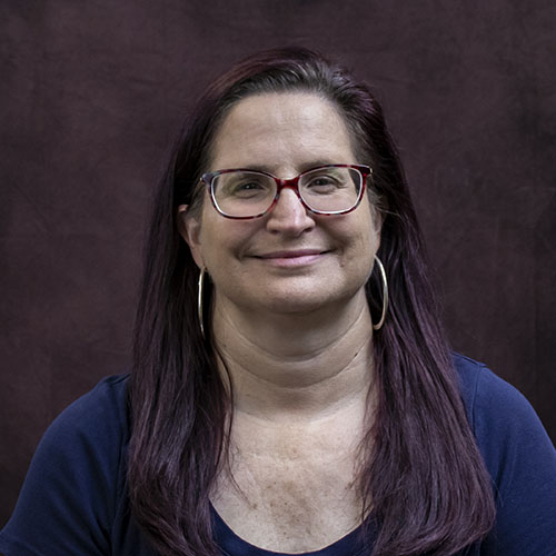 Smiling woman in a blue shirt with silver hoop earrings